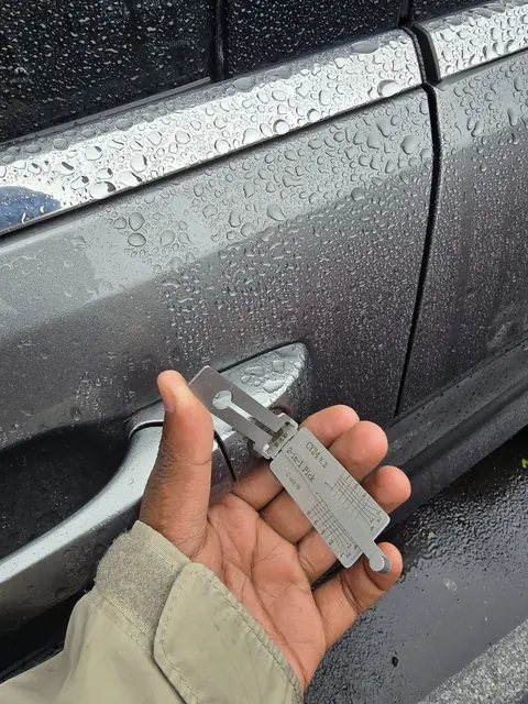 Locksmith using a pick tool on a car door lock