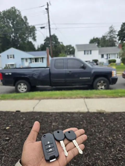 A new flip key and two transponder keys in front of a Chevy Silverado